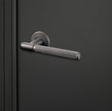 Moderne Lavuzo Cosenza deurklink Gun Metal met gekartelde greep op zwarte deur, rechteraanzicht