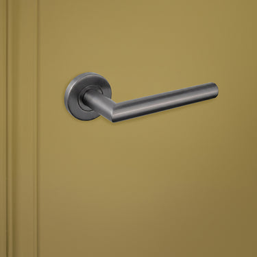 Gun Metal PVD gecoate deurkruk Mantua met ronde rozet op groene deur, linkeraanzicht