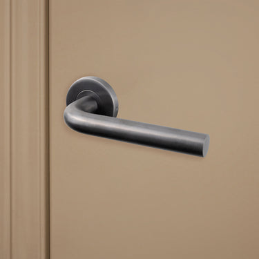 Gun Metal PVD gecoate Oristano deurklink op rond rozet gemonteerd op beige binnendeur, rechteraanzicht