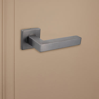 Strakke Gun Metal Viterbo binnendeurklink van Lavuzo op beige achtergrond, linkeraanzicht